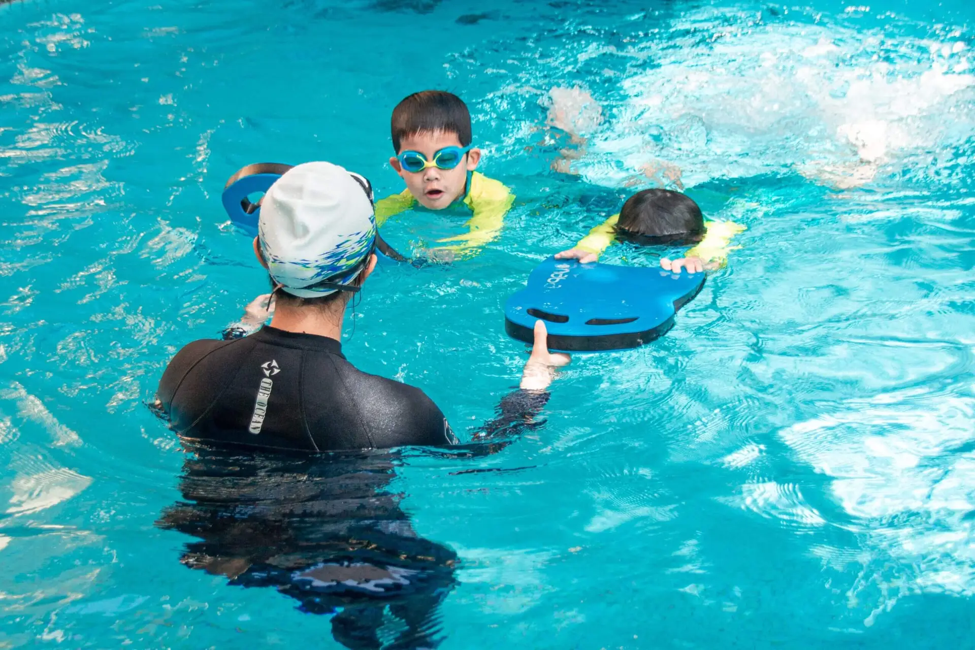 swimming coach coaching 2 kids in swimming pool