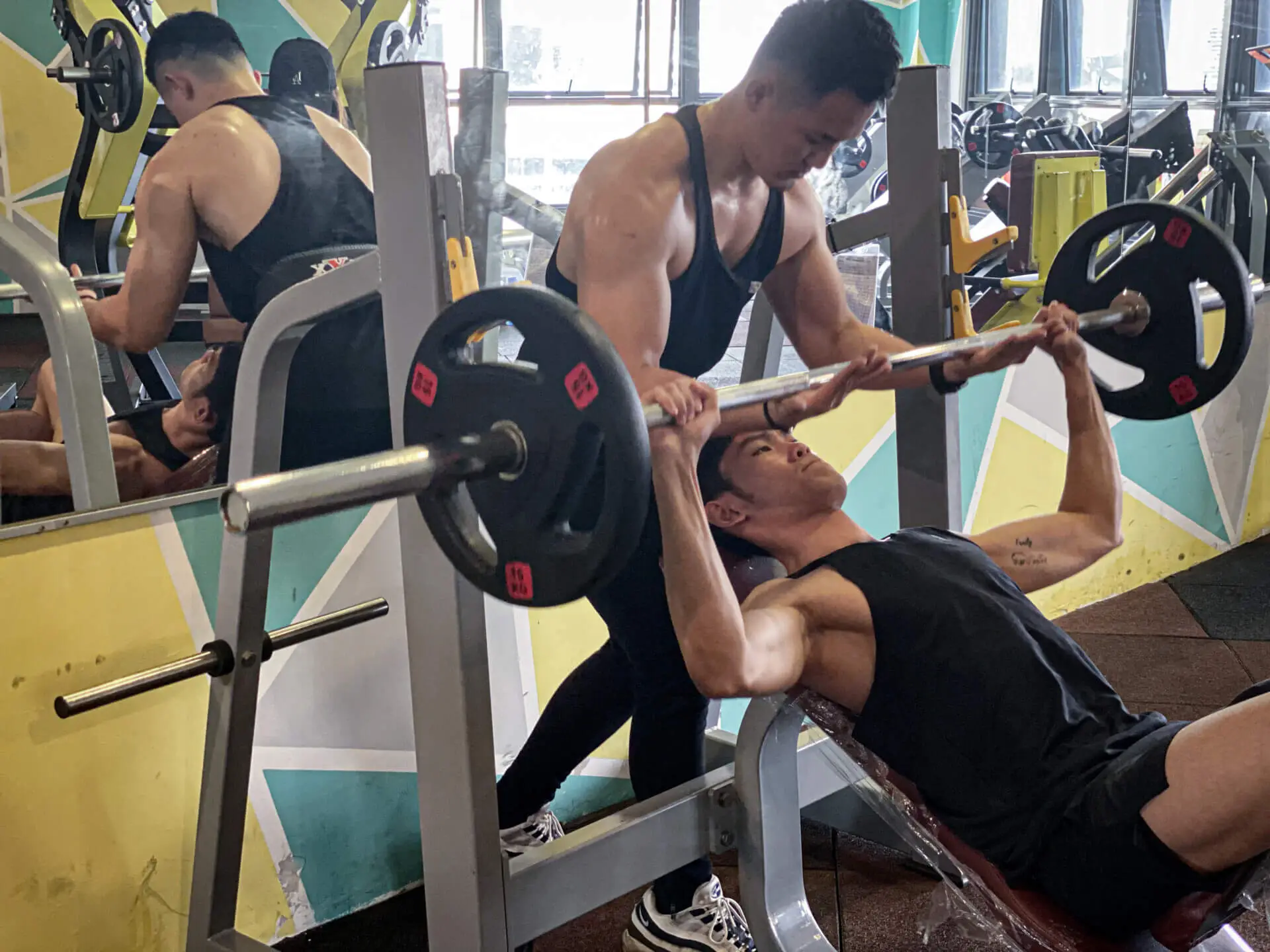 Personal Trainer coaching client doing barbell bench press with support