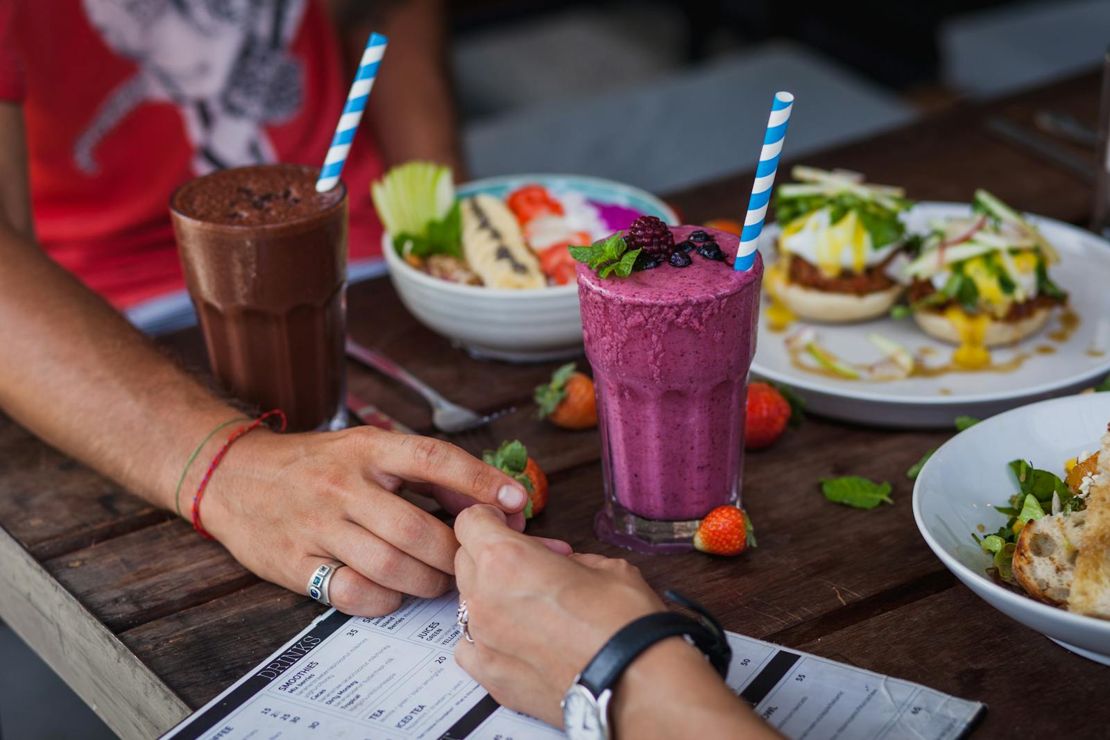 Crop couple eating various delicious dishes in summer cafe